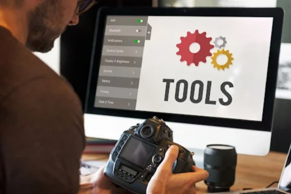 Man holding a DSLR camera while viewing “Tools” with gear icons on a computer screen.